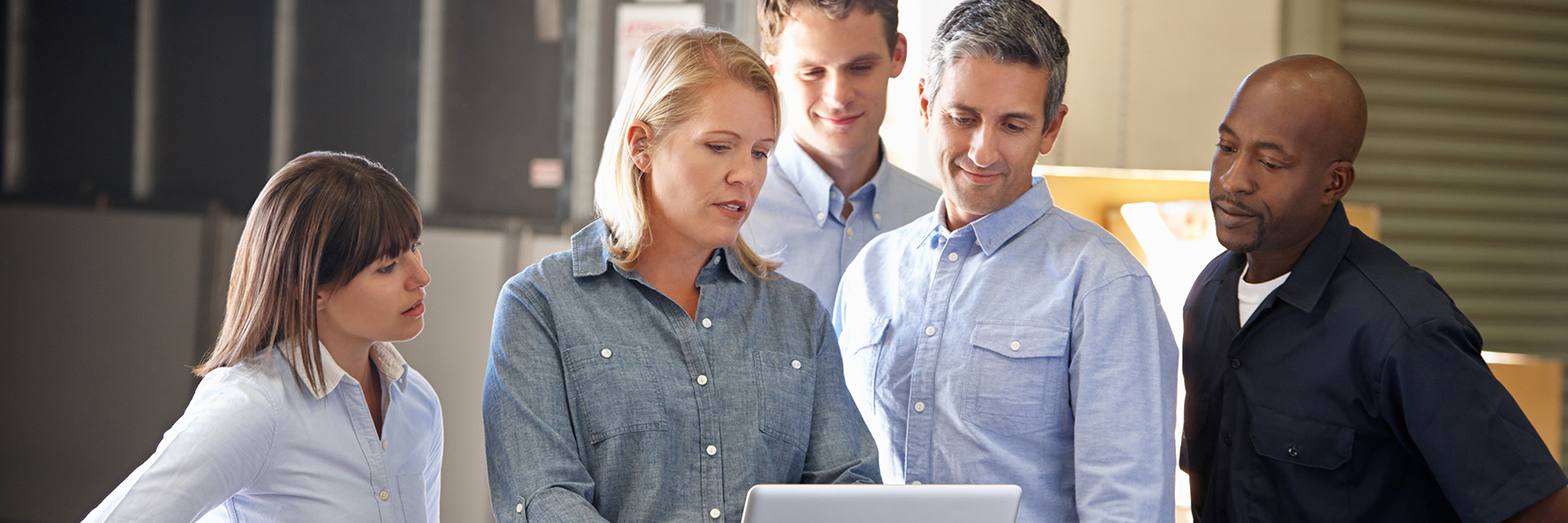 Photo of employees gathered around laptop